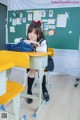 A young woman sitting at a desk in a classroom.